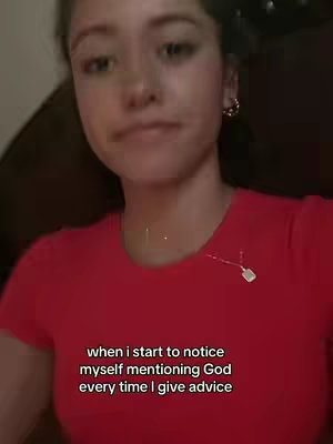 A young woman in a red t-shirt is shown in a close-up shot. The background is out of focus, suggesting an indoor setting. Text is overlaid at the bottom.