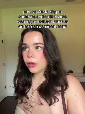 A young woman with dark hair and makeup is centered in the frame, looking slightly off-camera with a surprised expression. Overlayed text appears at the top. The lighting is natural, giving the image a casual, intimate feel.