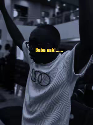 A photo with a man in a white t-shirt and glasses, with his arms raised in the air. The text \"Baba aah!......\" is overlayed on the image. It appears to be indoors and the image is in grayscale.