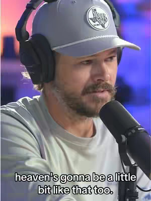 A close-up shot of a man with a beard wearing a gray hat, headphones, and speaking into a microphone. The background is blurred, and overlaid text at the bottom says 'heaven's gonna be a little bit like that too.'