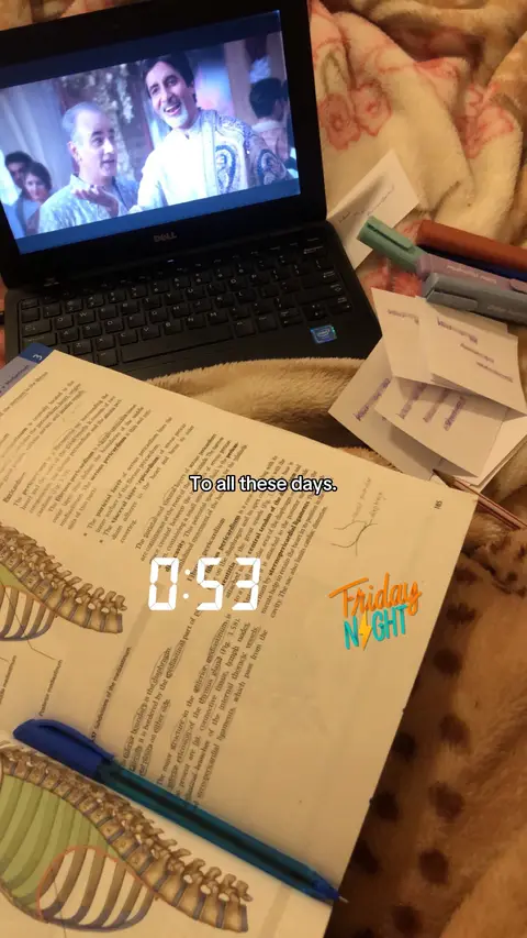 The image shows a laptop displaying a scene from a film, set on a bed with an open textbook and various study materials. The laptop screen is tilted upwards, showing a film scene where the actors are in traditional attire. Below the laptop is an open textbook with detailed anatomical diagrams and notes marked with a blue pen. Scattered around are flashcards, highlighters, and pens, suggesting a study session. At the bottom right of the image is a stylized text that reads 'Friday Night.'