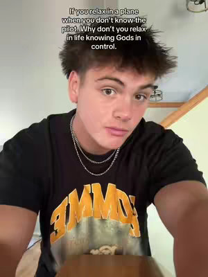 A young man with short, dark hair looks directly at the camera. He's wearing a black t-shirt with a yellow and orange graphic. Above him is an overlay of text that reads: "If you relax in a plane when you don't know the pilot. Why don't you relax in life knowing Gods in control."