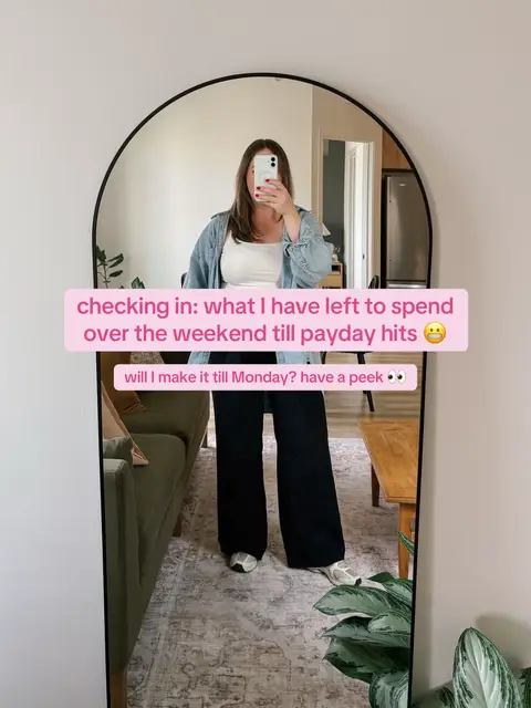 A full-length mirror captures a woman in a casual outfit. She holds her phone up, obscuring her face, reflecting the room behind her. The background shows a green sofa, patterned rug, and glimpses of other furniture indicative of a modern home. Text overlays are placed on the image, indicating the video's theme.