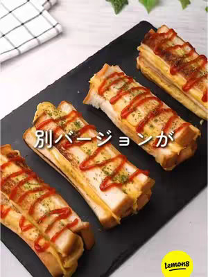 The cover image showcases four rectangular portions of a dish on a black surface. The dish appears to be a type of sandwich or roll with visible ingredients like egg and cheese, topped with red ketchup and green herbs. The background is a light color, the dish is positioned at an angle.