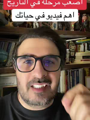 A man with glasses is centered in the frame, against the backdrop of a room with bookshelves.