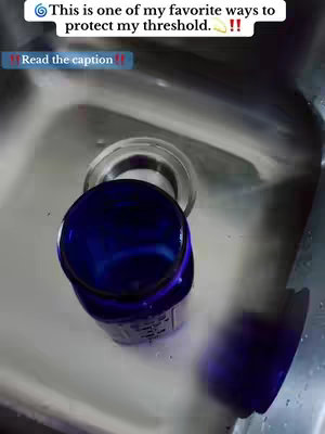 The image shows a deep blue glass bottle placed inside a stainless steel sink. Above the bottle, a clear glass or plastic ring may be from when the bottle was formerly sitting in the sink. There's text overlayed near the top. The content appears to relate to spiritual practices.