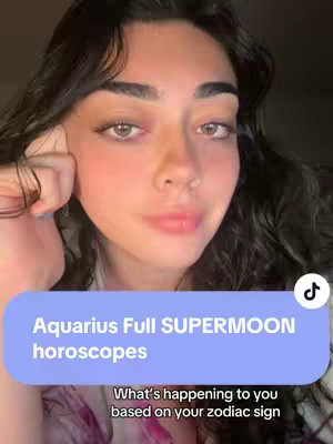 A dark image with a woman in the center, gazing upwards with neutral expression. A light blue rectangle at the bottom of the screen contains the text: "Aquarius Full SUPERMOON horoscopes
What's happening to you based on your zodiac sign". There's a "tiktok" logo on the top right.