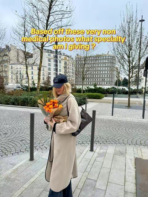 A woman in a light beige coat and a black cap stands on a cobblestone street, holding a bouquet of orange flowers. Behind her are buildings and trees with a cloudy sky. The image is framed, focusing on the woman and her surroundings, with a text overlay.