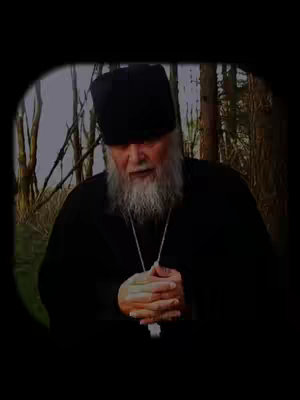 The cover image shows a medium shot of an older man in religious attire, appearing to be speaking. He wears a black hat and a black robe, with a long, white beard. His hands are clasped in front of him, and a silver chain with a cross pendant is visible. The background seems to be a blurred forest setting, with visible tree trunks. The image has a dark, vignette-style border, focusing the viewer's attention on the man.