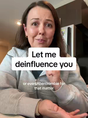 A woman with medium-length brown hair sits in front of a kitchen or home setting. She wears a light gray hoodie and looks directly at the camera with a slight smile. A white text box is centered in the frame, it reads Let me deinfluence you.