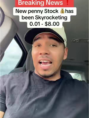 A man is filmed inside a car. The man is in a car, sitting in the driver's side. Above the man is a red rectangle that says, "Breaking News!". In the lower third of the rectangle is the text, "New penny Stock has been Skyrocketing".