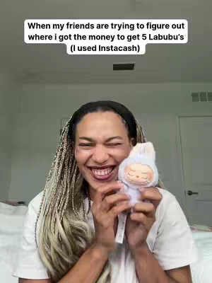 A person with braided blonde hair smiles broadly while holding a Labubu doll. Text overlays a white background.