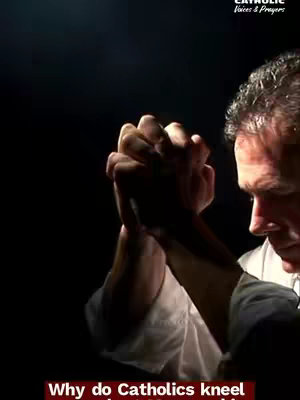 A man in a white shirt has his hands clasped together in prayer in front of his chest, the background is dark with a dim light on the face to give a reverential mood, with the overlay text saying 'Why do Catholics kneel'.