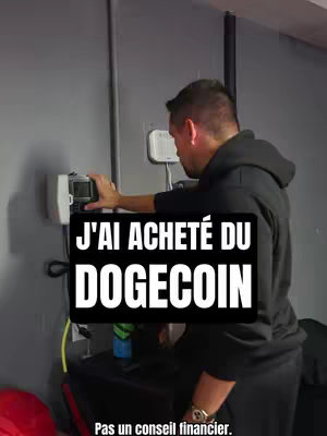 The cover image shows a man standing in a room. He's wearing a black hoodie and looking down at a device. Overlayed on top of the image is a black rectangle with white text stating 'J'AI ACHETÉ DU DOGECOIN'. At the bottom is more white text 'Pas un conseil financier.'