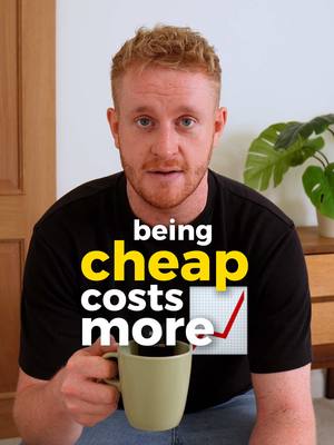 A man with short, ginger hair is centered, holding a coffee mug and looking directly at the viewer. Overlay text in yellow and white states 'being cheap costs more'. An upward trending graph icon is incorporated into the text design. The background is a simple domestic setting.