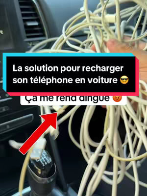 The image shows the interior of a car with a focus on the center console. A large bundle of white charging cables is held in the foreground, obscuring much of the car's details. A red and black text box overlays the image, displaying text related to recharging a phone in a car and an angry emoji. A red arrow points towards a cable.
