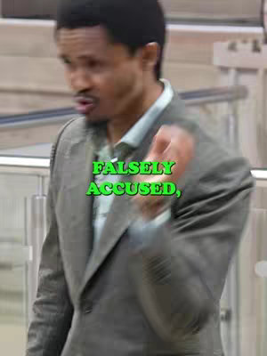A man in a gray suit is shown gesturing with his hand, with a green text overlay that reads "FALSELY ACCUSED,". The background is blurred.