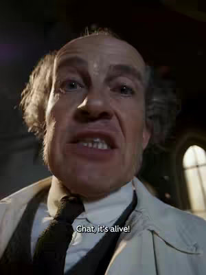 A close-up shot of a man with a bald head and white hair on the sides, dressed in a white lab coat over what appears to be a vest and tie. The man is looking towards the camera with an excited expression, and the text 'Chat, it's alive!' is overlaid on the bottom.