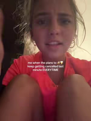 A selfie-style video shot with a young woman. The woman is in the foreground with the upper part of her body visible; she faces the camera and appears to be talking. A text overlay appears on the screen.