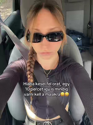 A woman is sitting in the driver's seat of a car, looking at the camera. She is wearing sunglasses and a black top, and her hair is in a side braid. Text is overlaid on the bottom.