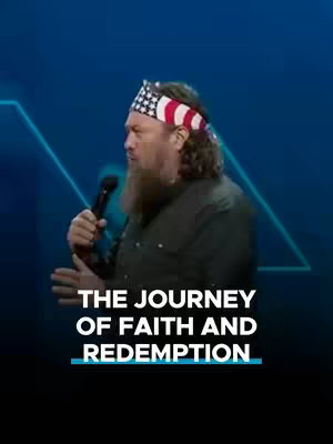 The cover image shows a medium shot of a man with a beard and an American flag bandana, holding a microphone in his right hand. He is on a stage with a dark blue background and some white graphical elements. Below him, in white text, is a line that reads, "THE JOURNEY OF FAITH AND REDEMPTION".