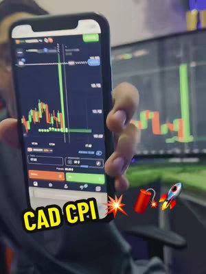 The image shows a person holding a smartphone displaying a stock chart and another screen behind it with a similar chart. The smartphone is in focus, charts in red and green are displayed. Text overlay at the bottom reads 'CAD CPI'. There are also emojis of a bomb and a rocket.