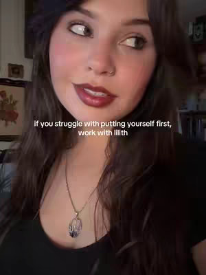 A medium shot features a young woman with long, dark hair, a nose piercing, and red lipstick. The background is slightly blurred, with hints of a room. Overlayed text offers advice about self-prioritization and Lilith.