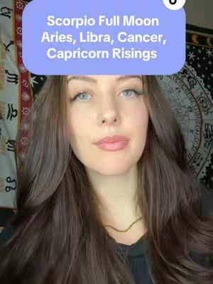 A woman with long brown hair and blue eyes is centered in the frame, with a light purple text box above her head. The background features a tapestry with celestial and floral patterns.