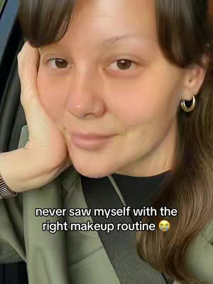 A close-up shot of a woman's face, with her head resting on her hand. She has fair skin, brown eyes, and dark hair. The background suggests she is inside a car.