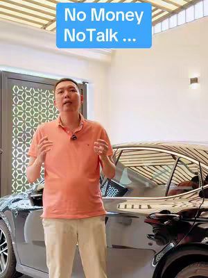 A man stands in front of a black car, likely a luxury model, with a residential background. He wears a salmon-colored polo shirt and beige pants, gesturing with his hands while facing the camera. Above him, a light blue rectangular box displays the text "No Money NoTalk ...".