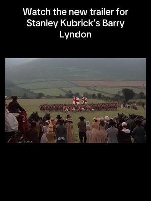 The image is a movie still of a historical battle scene, likely from the film "Barry Lyndon." The scene is set in a large, grassy field with a line of soldiers in the background and spectators watching in the foreground. The color palette is muted, with greens and browns dominating the scene, providing a classic, historical feel. The layout is balanced, using the positioning of the soldiers and spectators to create depth and guide the viewer's eye.