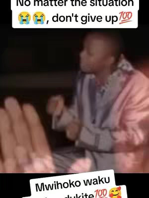 The cover depicts a low-quality, slightly blurry image of a man, likely African, with short dark hair, captured from the chest up. The man is positioned slightly off-center to the right, with his face turned towards the left. On the left, a blurred hand is visible in the foreground. In the upper part of the image, there is overlaid text. At the bottom of the image, white text is set against a black background.