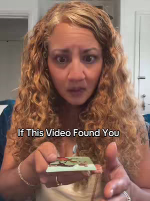 A woman with long, curly blonde hair gazes directly at the camera with a surprised expression. She holds a tarot card up, the text overlayed: 'If This Video Found You'. The background shows a residential interior, with a door and some wall visible.