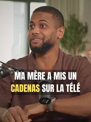 A man with a dark complexion and short dark hair looks towards the left side of the frame with a surprised expression. He has short, dark facial hair and is wearing a brown button-down shirt. Overlaid on top of the image is a text overlay with white text on a dark background, and yellow text on a dark background.