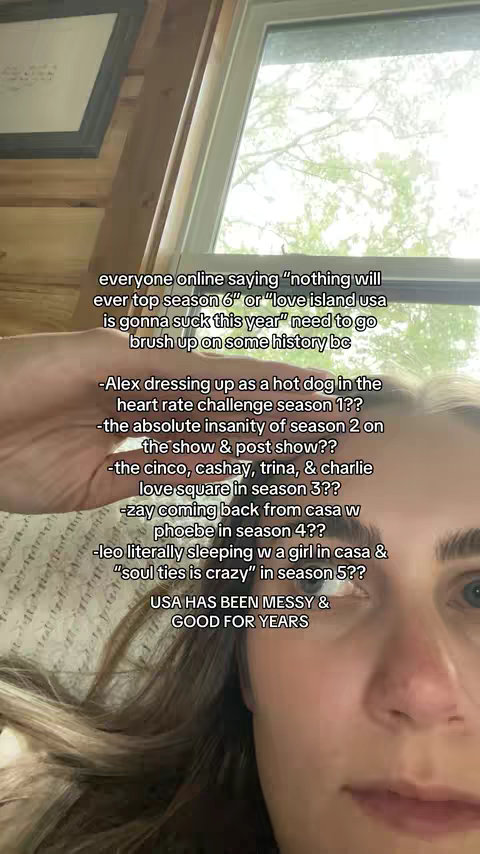 A selfie-style shot featuring a person's face, positioned closely to the camera, with text overlayed on the image. The background is blurred, but appears to be an indoor setting. The person has long hair, and looks directly at the camera. The composition is simple, with the person's face taking up a significant portion of the frame.