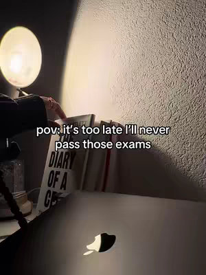 A dimly lit interior scene with a wall and shelf. On the shelf are books and a laptop with the Apple logo. A lamp is on, casting a warm glow. The image has text overlayed explaining a study tip.