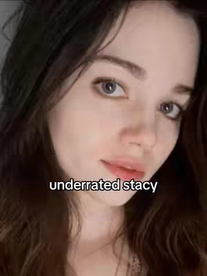 The cover image features a close-up of a young woman's face, with visible dark hair framing her face and a soft gray backdrop. The overlay text "underrated stacy" is placed at the bottom, written in white. Her eyes are a muted blue, and her expression is neutral.