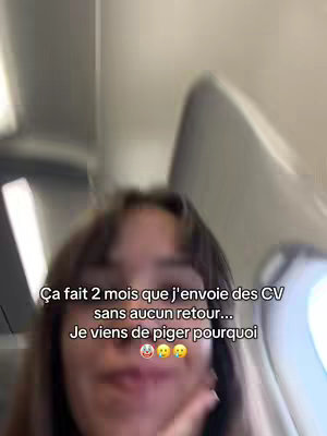 A selfie-style video taken from a slightly low angle inside an airplane. The subject is a young woman with dark hair, partially covering her face. The bright interior of the plane is visible in the background.