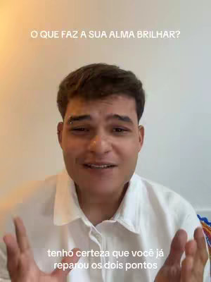 A man in a white shirt is centered in the frame. Text overlays the top and bottom of the frame in white. The man has short, dark hair and a small, curved piercing in his left eyebrow. He is smiling slightly with his hands up.