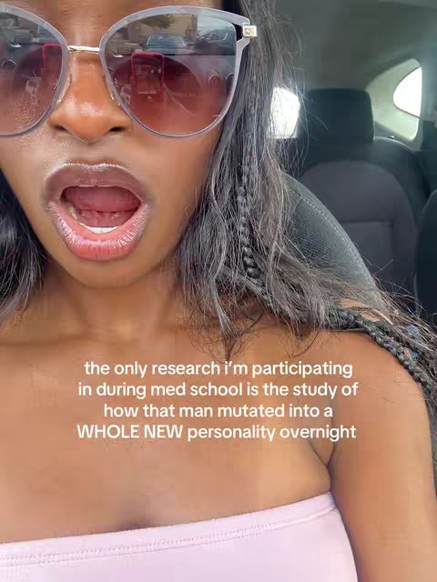 A selfie featuring a woman with dark hair wearing large, tinted sunglasses. Her mouth is open, with text overlaid on the image. The background suggests the interior of a car.
