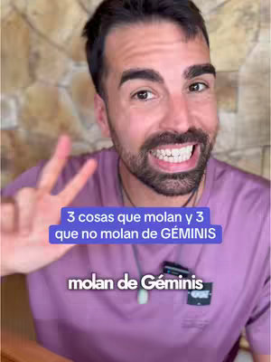A man with a short beard and dark hair is shown from the chest up, smiling towards the camera and holding up two fingers. He is wearing a purple t-shirt and a silver necklace with a small, light-green pendant. The background appears to be a wall with a textured, beige surface. Text overlays in blue and white are placed in the image; one says '3 cosas que molan y 3 que no molan de GÉMINIS' and the other 'mloan de Géminis'.