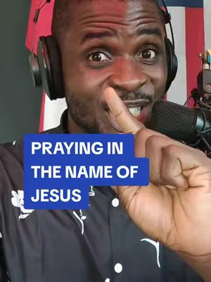 A man with a dark complexion wearing a patterned shirt and headphones is the main focus. A finger is placed over his lips. Overlaid on his chest is a blue rectangular box of text that says "PRAYING IN THE NAME OF JESUS."