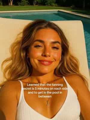 A woman with long blonde hair is laying down as she is smiling and looking at the camera. She is wearing a white tank top, a gold necklace and earings. The background is out of focus, but appears to be a pool.