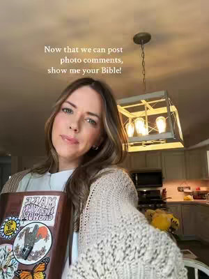 A woman holds a Bible, smiling at the camera. Text overlay asks viewers to show their Bibles. The background includes a kitchen with a pendant light.