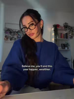 The cover image features a young woman with long dark hair and glasses, wearing a blue long-sleeved top. She is seated indoors in a room, with a bright light source illuminating her face. Background details include a display of photos and decorative shelving.