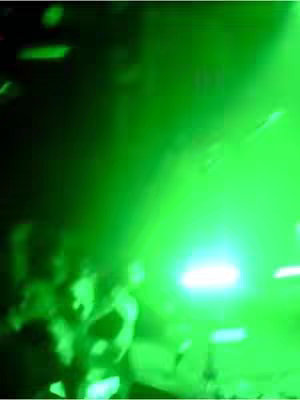 The cover image is dominated by a vibrant green hue, possibly the result of strong lighting, with indistinct shapes silhouetted against it, suggesting a crowded or energetic environment. The image is out of focus, creating a sense of movement or dynamic atmosphere.