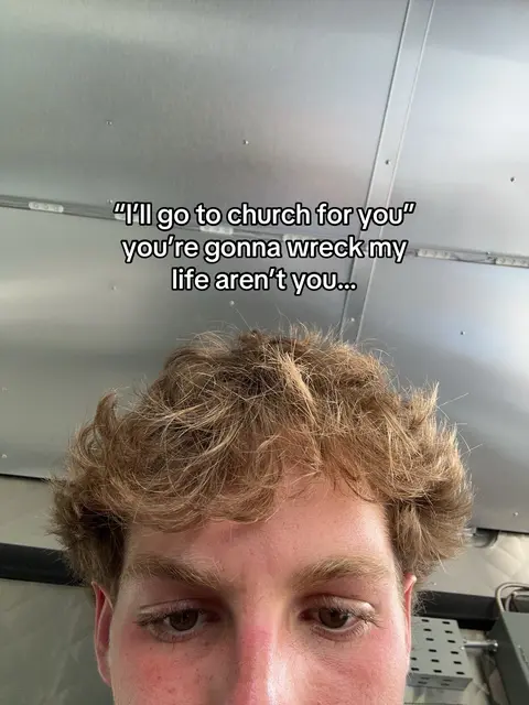 A close-up shot of a young man's face with curly light brown hair. Text overlayed above him with a casual font. The background shows a slightly reflective, metallic surface.