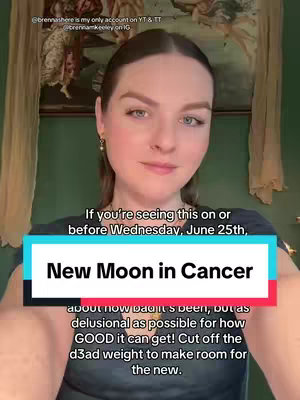 A woman with light skin and fair hair is centered in the frame, looking directly at the camera with a slight smile. She is in front of a green wall adorned with a draped curtain and a painting. Overlaid on the image are several text elements positioned near the bottom. The main element is a rectangular box in shades of blue and red with text that reads "New Moon in Cancer". Another box in the upper part of the screen displays information on the user's social media account, with the usernames. The text below the main title gives additional context and instructions, written in a dark font.