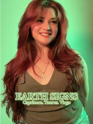 A woman with long red hair smiles at the camera. Text overlayed on the bottom reads 'EARTH SIGNS' in a glowing green font, with the names of three zodiac signs underneath. The background is a gradient of green.