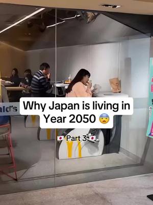 The image shows the inside of a McDonald's restaurant shot through a glass door. A white text box with rounded corners, reading "Why Japan is living in Year 2050 😮", is overlaid near the middle. Beneath it, a smaller text box says "Part 3" with the Japan flag. Inside, several people are seated at tables with individuals in the background